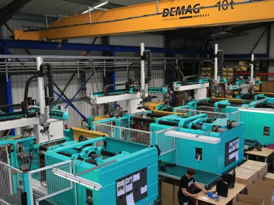 View into the RH Kunststofftechnik GmbH production hall with several injection moulding machines, handling robots and an overhead crane.
