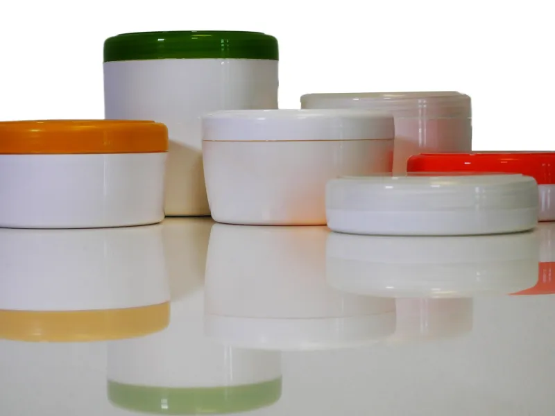 Several plastic cosmetic jars in different sizes and lid colours, an example of packaging solutions by RH Kunststofftechnik GmbH.