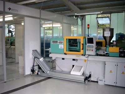 View into the production area with an Arburg injection moulding machine and automatic material feed.